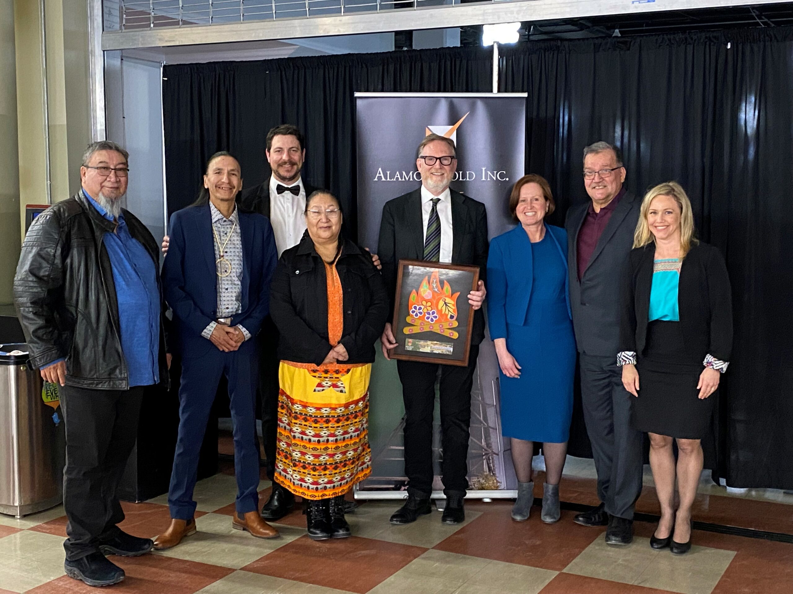 Group of people standing side by side smiling and holding the Reconcilation Award from the Manitoba Prospectors and Developers Association.